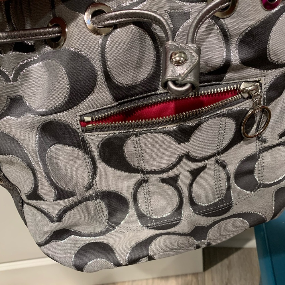 Grey metallic coach bucket purse.